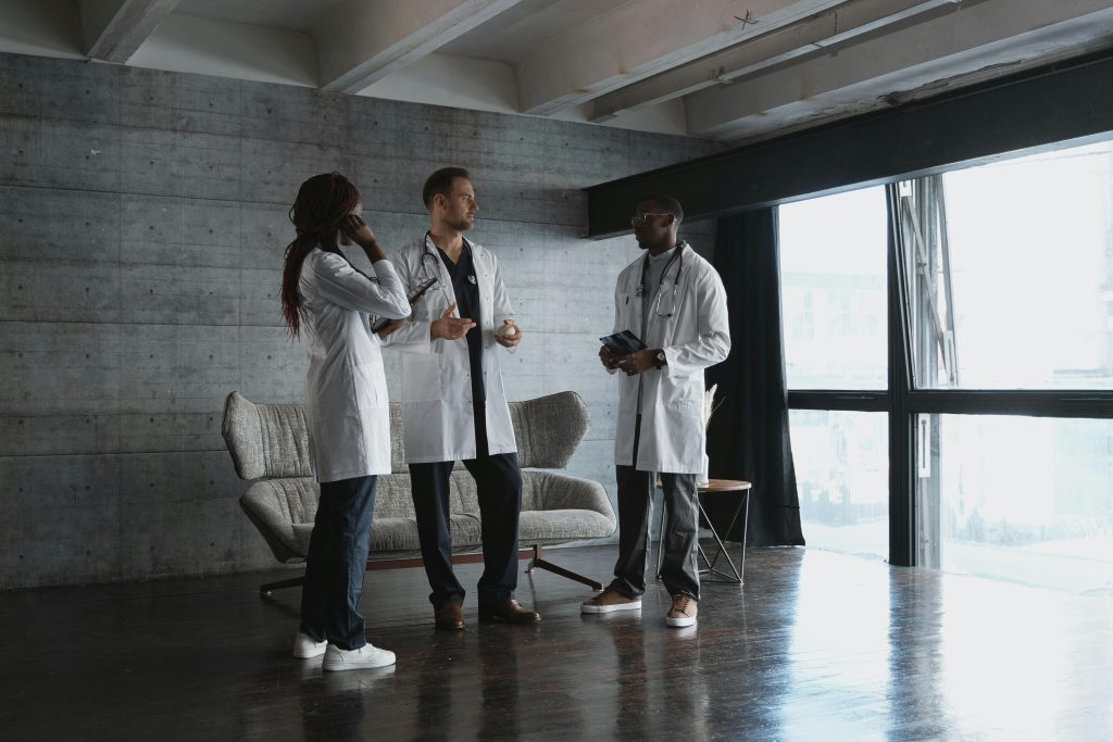 Three doctors in a modern office discussing medical matters in natural light.
